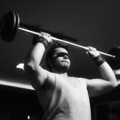 Sportif exécutant un développé militaire debout avec barre